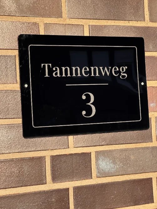 Hausnummernschild aus schwarzem Acryl mit der Aufschrift Tannenweg 3